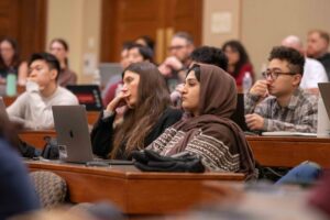 Close up of 3 audience members watching lecture